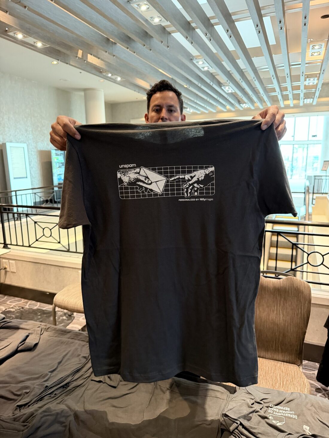 Merch Troop staffer holding up a finished custom-printed shirt in a venue lobby